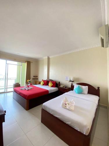 a hotel room with two beds with red sheets at Four Rivers Hotel in Stœ̆ng Trêng