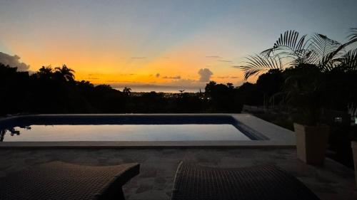 a swimming pool with a sunset in the background at Casa Vista Mar in Río San Juan