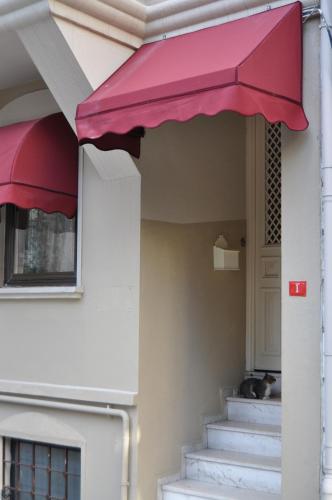 a cat laying on the porch of a house with a pink awning at Taksim Home in Istanbul