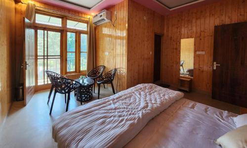 a bedroom with a bed and a table and chairs at riverview villa in Bīr