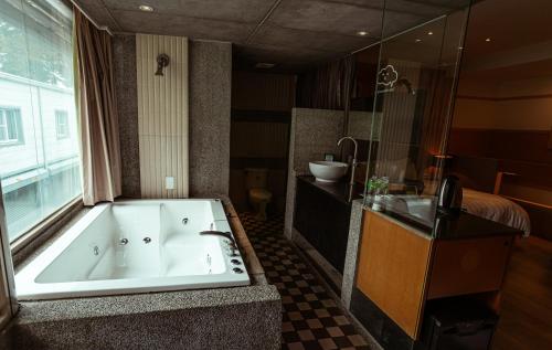 a large bathroom with a tub and a bed at Jungle City Motel in Chiayi City