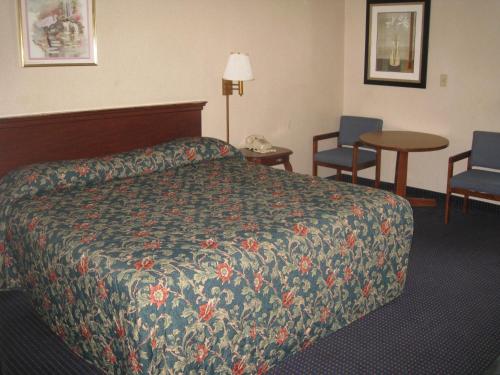 a hotel room with a bed and a table and chairs at Budget Inn Temple Hills in Temple Hills