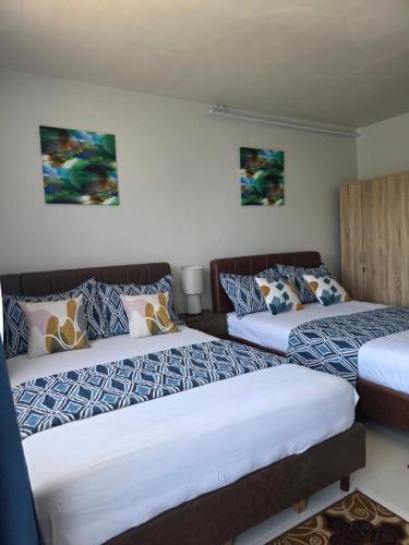 a room with two beds and two paintings on the wall at VERDANT by Vista Manors Deluxe Rooms with Balcony, Gym and Swimming Pool in Puerto Princesa City