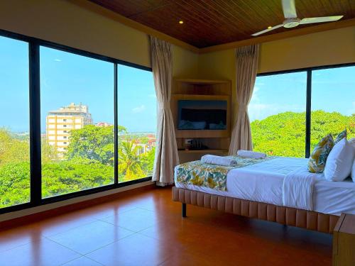 a bedroom with large windows and a bed with a view at Hotel Shoolin Grand in Mangalore