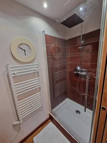 a bathroom with a shower with a clock on the wall at Belle Maison bois avec piscine proche de la plage in Landéda
