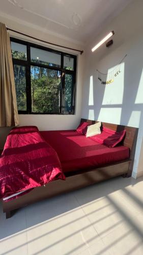 a red bed in a room with a window at riverview villa in Bīr