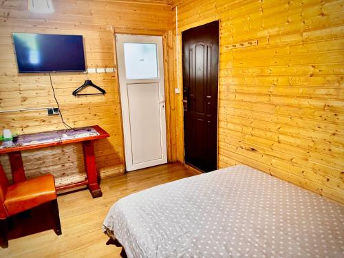 a bedroom with a bed and a tv on a wooden wall at Casa Beijing in Braşov