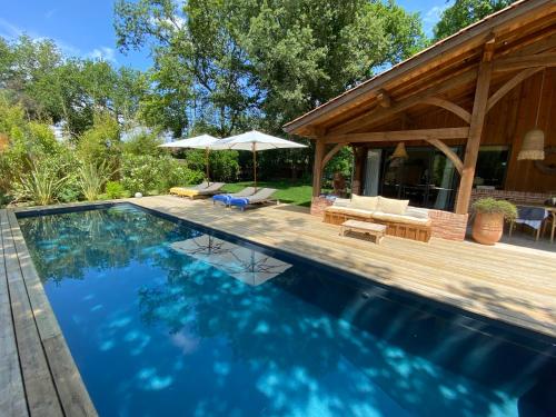 a swimming pool in a backyard with a house at L Esprit du Cap in Belin-Beliet
