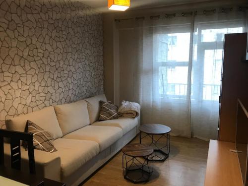 a living room with a white couch and a window at Apartamento cerca de la playa in Viveiro