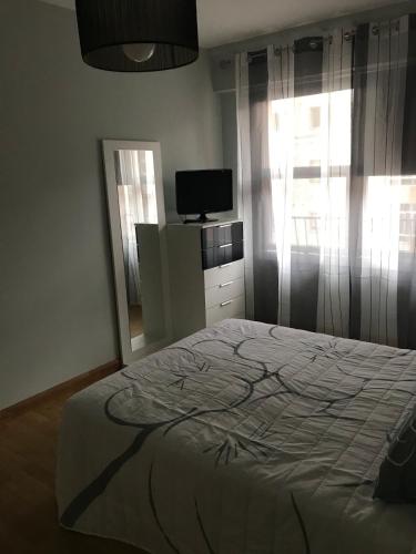 a bedroom with a bed and a tv and a window at Apartamento cerca de la playa in Viveiro