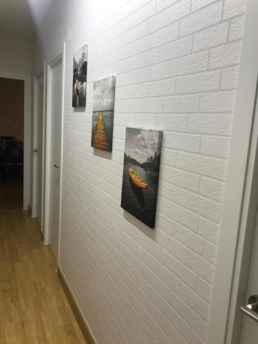 a wall with four pictures on a brick wall at Apartamento cerca de la playa in Viveiro