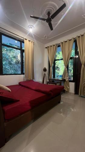 a bedroom with a red bed with windows and a ceiling fan at riverview villa in Bīr