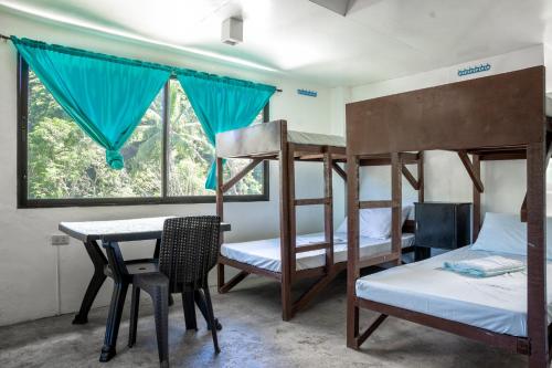 a room with two bunk beds and a table and chairs at Aroha Hostel in Coron