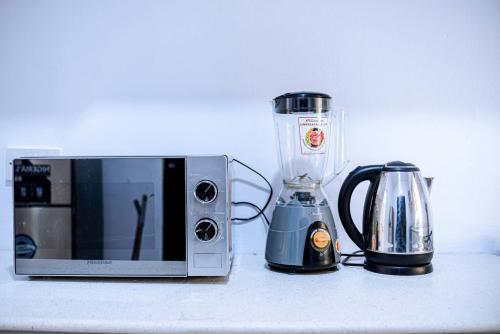 a blender and a microwave sitting on a counter at Stylish Lekki Phase 1 1BR Flat 24/7 Power in Lekki Phase 1