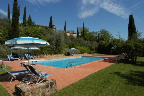 una piscina con sillas y sombrilla en La Valle Appartamenti Per Vacanze, en Montaione