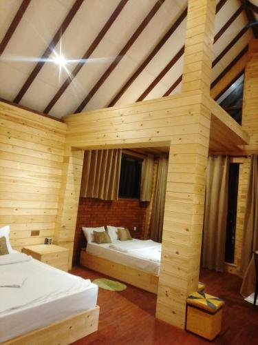 a bedroom with two beds in a wooden room at The Palace Eco Cottage in Ella