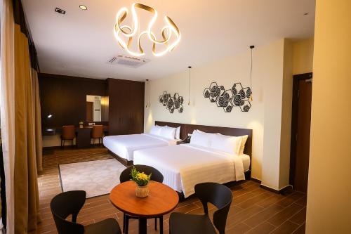 a hotel room with two beds and a table and chairs at Elissa Hotel & Suites in Kangar