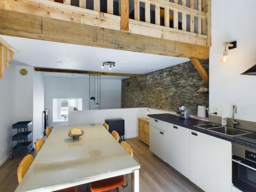 a kitchen with white cabinets and a stone wall at La Rocha in La Roche-en-Ardenne