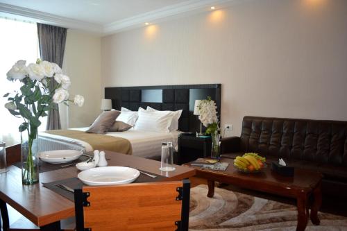 ein Hotelzimmer mit einem Bett und einem Tisch sowie einem Esszimmer in der Unterkunft Tilal Almadina Hotel & Suites in Amman