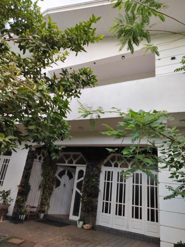 a white house with white doors and trees at Kandy Home stay in Katugastota