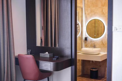 a bathroom with a sink and a red chair at Elissa Hotel & Suites in Kangar