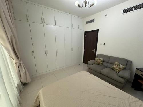 a living room with a couch and white cabinets at Big flat 3 bedrooms, in floor 15 full service in Sharjah