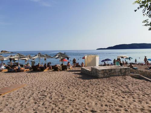 a group of people sitting on a beach at Apartment Aleksic Becici in Bečići
