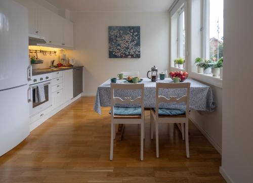 cocina con mesa con 2 sillas y cocina con armarios blancos en Ås Sentrum Suite, en Ås