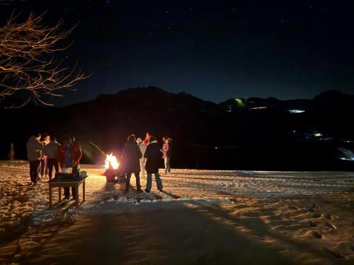 a group of people standing around a fire on a beach at night at Mösslacher's Ferienwohnungen in Hermagor