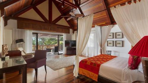 a bedroom with a canopy bed and a desk and a television at Sankhara Luxury Private Beach Villas in Poste Lafayette