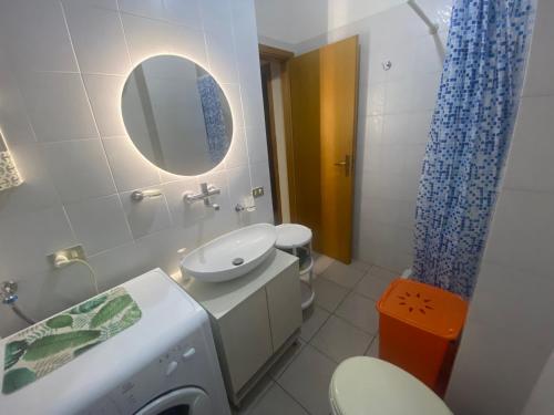 een badkamer met een wastafel, een toilet en een spiegel bij Casa Marylu con giardino in Marina di Schiavonea