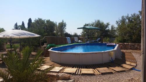 a hot tub in a yard with a table and an umbrella at Masseria Fachechi in Nardò