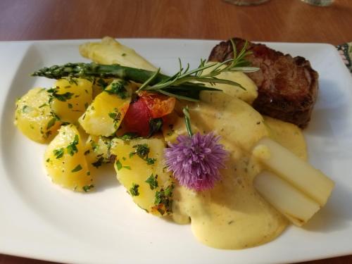 a white plate of potatoes with a purple flower on it at Hotel-Restaurant Fischerwirt in Gratwein