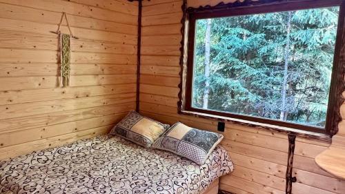 a bed in a log cabin with a window at Eco glamping - Carpathians. Retreat hub Dzin Space in Verkhovyna