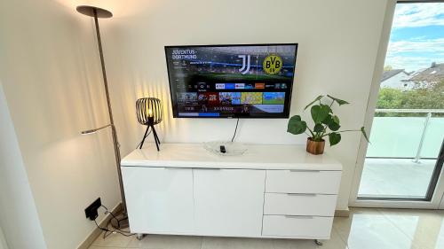 a tv on top of a white cabinet in a room at Himy Home - Moderne Wohnung mit große Dachterrasse in Dormagen