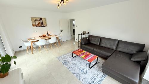 a living room with a black leather couch and a table at Himy Home - Moderne Wohnung mit große Dachterrasse in Dormagen