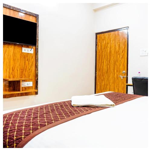 a room with a bed with a tv and a door at Navneeta Grand Near Assi Ghat Full AC Room in Varanasi
