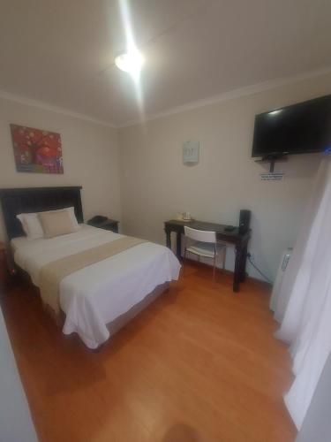 a bedroom with a bed and a desk and a television at The Comfort Zone - Mthatha in Mthatha