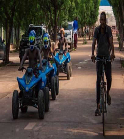 a group of men riding on atvs and motorcycles down a street at Orpheus Dream Village Hotel in Bamako