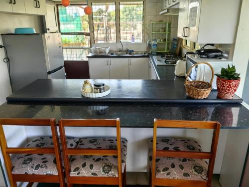 a kitchen with a large black counter with two chairs at Ensuite Double Bedroom in Nadi