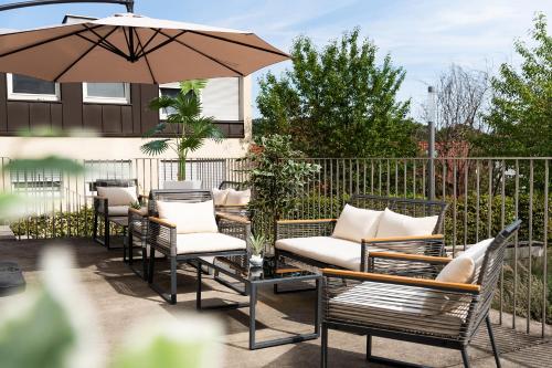 a patio with chairs and a table with an umbrella at Hotel Bergamo Modern & zentral in Ludwigsburg Klimaanlage 3 Min zum Schloss WLAN Frühstück optional besonderes nachhaltiges Stadthotel in moderner Holzbauweise in Ludwigsburg