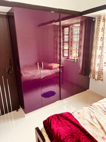 a bedroom with a purple cabinet with two beds at Kannada Maathe Home Stay- 2km to Golden Temple-Tibet camp in Kushālnagar