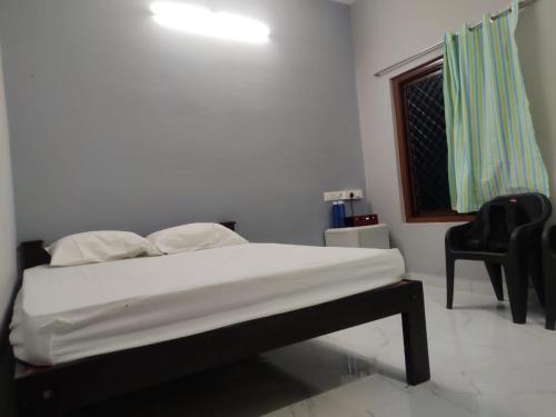 a bedroom with a bed and a window and a chair at Little Nest Residency in Kuilapayam