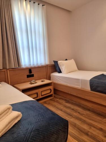 a hotel room with two beds and a window at Palorto Inn in Gjirokastër