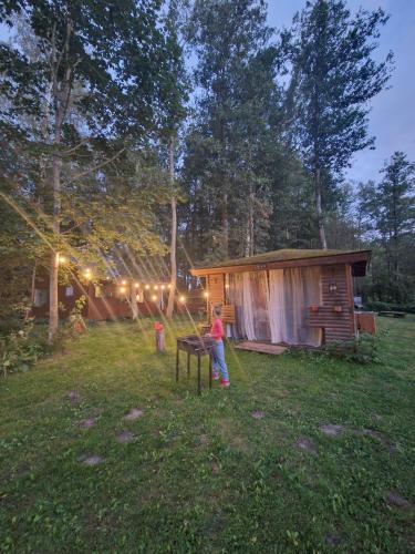 a woman standing in a yard in front of a cabin at Māja pie ezera in Stacija Aglona