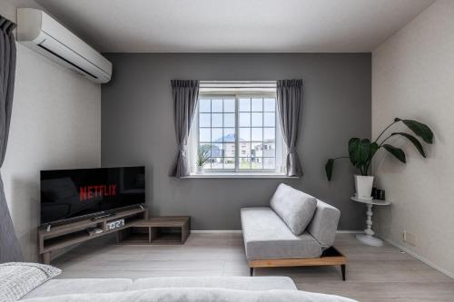 a living room with a television and a chair at カーサブルー御殿場 in Gotemba
