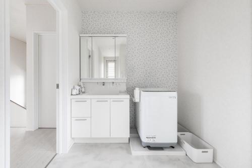 a white bathroom with a sink and a mirror at カーサブルー御殿場 in Gotemba