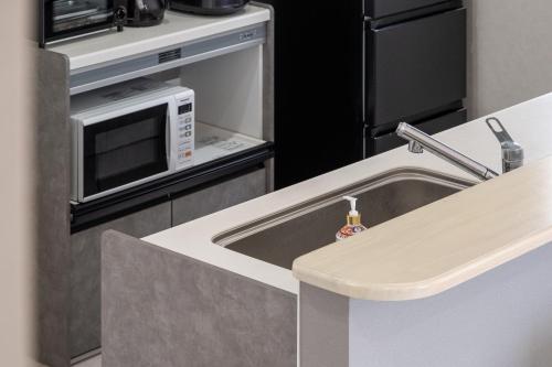a kitchen with a sink and a microwave at カーサブルー御殿場 in Gotemba