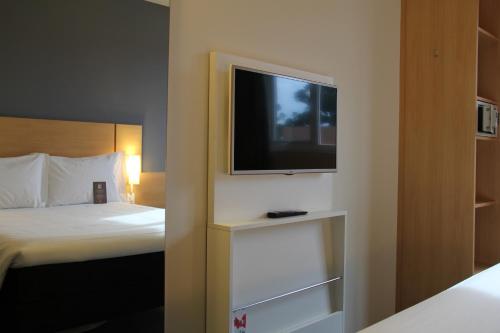 a bedroom with a bed and a tv on a wall at ibis Chapeco in Chapecó