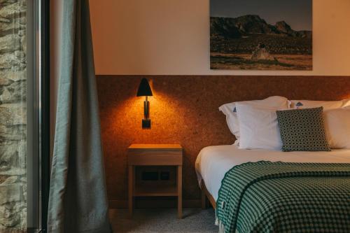 a hotel room with two beds and a table with a lamp at Estrela Serenity - Resort in Folgosinho